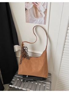 Detailed shot of caramel Hobo bag with fashion charms on a silver suitcase