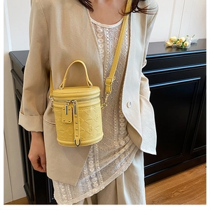 Detail of yellow quilted bucket bag featuring dual zippers and adjustable crossbody strap