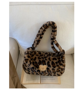 Détail du sac à main en peluche léopard avec écusson d'ours mignon sur texture douce