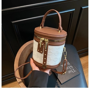 Close-up of contrast color bucket bag with metallic gold zippers and leather handle