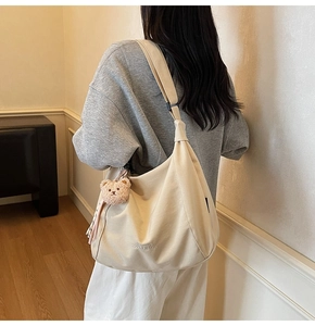 Detail of off-white canvas tote bag with adjustable strap and cute plush bear charm