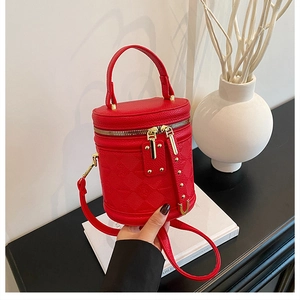 Detail view of red quilted leather cylindrical bag with gold zipper and rivets decoration