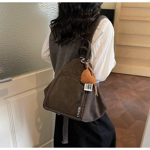 Détail d'un sac à dos vintage marron café avec pendentif cœur sur le dos du mannequin