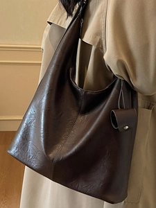 Large dark brown vintage PU leather tote bag with decorative charm on model