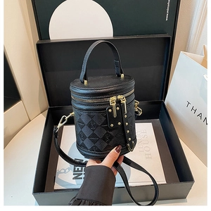 Close-up of black quilted bucket bag with gold hardware inside luxury gift box