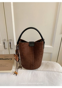 Close-up of retro brown bucket bag with matte suede texture and floral bead charm