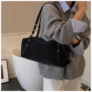 Close-up of matte black shoulder bag with gold hardware and stylish metal eyelets