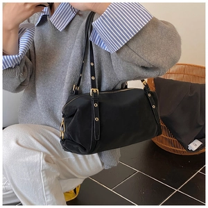 Close-up of black nylon shoulder bag with adjustable gold eyelets on the strap
