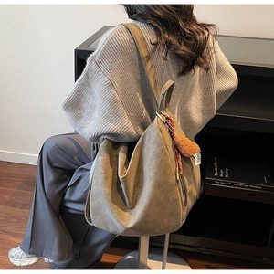 Détail du grand sac cabas en daim vert olive avec pendentif en peluche et large sangle