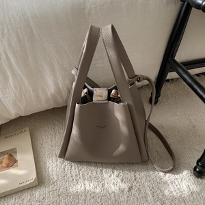 Detail of taupe litchi grain bucket bag with MIQIER logo and gold snap hardware