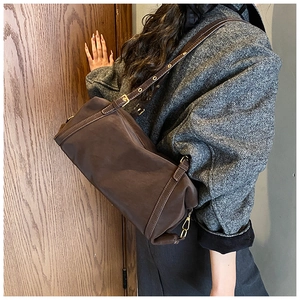 Detail of vintage dark brown Boston bag in textured leather with golden metal accents