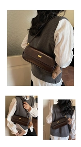 Detail of dark brown leather baguette bag with gold hardware and plush bear charm