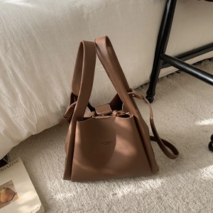 Close-up of brown litchi pattern leather bucket bag with gold buckle and brand logo