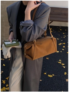 Close-up of caramel cylindrical suede shoulder bag with gold hardware and zipper