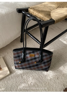 Gros plan d'un sac cabas rétro à carreaux avec logo doré sur un tapis crème