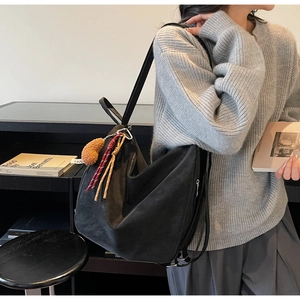 Détail d'un grand sac cabas noir avec pendentif en cœur et cordons tressés colorés