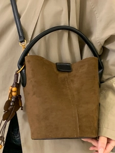 Brown suede bucket bag with tassels and black leather handles for stylish winter outfits