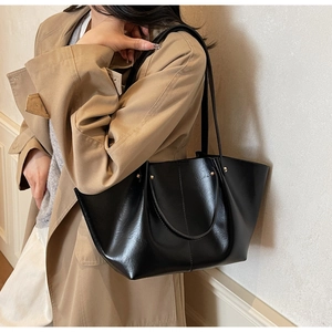 Schicke schwarze große Tragetasche aus glänzendem PU-Leder als stylische Schultertasche am Model