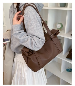 Side view of a large dark brown leather tote bag with pebble texture and wide shoulder strap