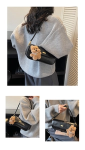 Detail of black vintage baguette bag featuring a cute teddy bear charm and gold buckle