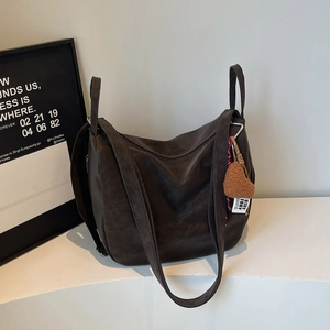 Détail d'un cabas marron foncé avec charm cœur et texture mate sur fond minimaliste