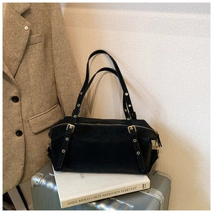 Detailed view of a black retro shoulder bag on a silver suitcase with golden hardware