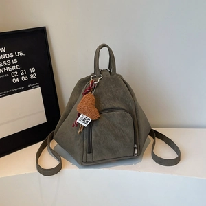 Détail du sac à dos géométrique vert olive en cuir mat avec un charme cœur en peluche