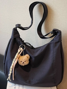Navy blue nylon crescent tote bag with teddy bear pendant and wide shoulder strap