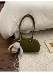 Detailed view of an olive green suede baguette bag with a cute plush rabbit charm