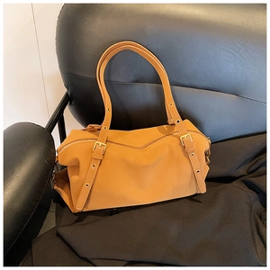 Detail view of the mustard yellow leather boston bag with adjustable strap and gold hardware