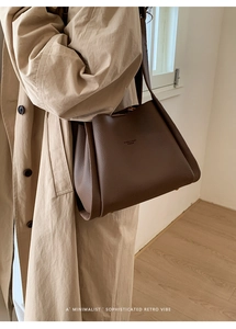 Close-up of deep brown lychee texture leather bucket bag with fashion logo lettering
