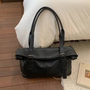 Macro detail of black litchi grain leather shoulder bag with decorative metal buckle