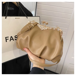 Détail du sac plissé beige avec fleur en cristal et fermoir kiss-lock doré élégant