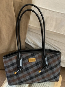 Sac cabas à carreaux classique avec poignées en cuir noir sur fond vintage élégant