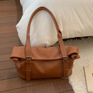 Close-up of caramel brown pebble leather texture and buckle strap details on tote bag