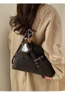 Détail du sac cabas en daim marron foncé avec miroir cœur et nœud léopard sur le modèle