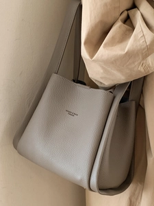 Elegant taupe litchi grain leather bucket bag with wide base and slim shoulder straps