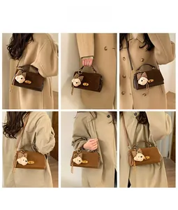 Detail shot of mini crossbody bag with metal twist lock and cute plush bear charm