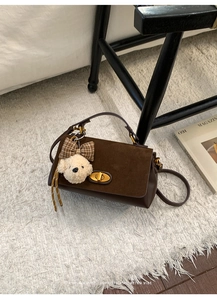 Detail of vintage brown shoulder bag with golden lock and plaid bow bear charm
