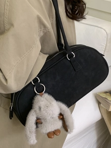 Minimalist black crescent baguette bag with fluffy bunny charm on a model's shoulder