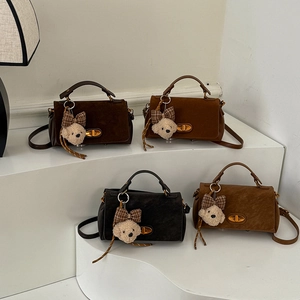 Detailed view of four retro faux suede mini crossbody bags with cute plush bear charms