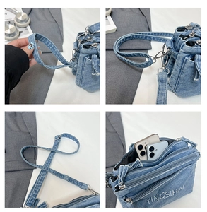 Detail of blue denim crossbody bag featuring three zipper pockets and white embroidery