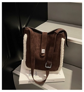 Close-up of brown suede bucket bag with white faux shearling trim and metal buckle