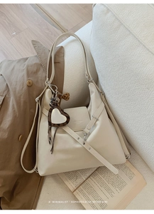 Détail du sac cabas rétro blanc crème avec breloque cœur léopard sur un canapé blanc