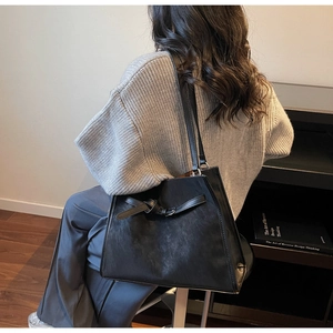 Chic black leather tote bag with unique knot detail shown on model in a modern home setting