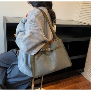 Side view of large grey-green tote bag with silver buckle and brown trim details