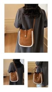 Detail of brown suede bucket bag with white faux shearling trim and silver metal clasp