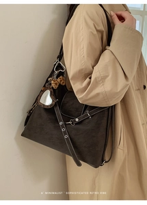 Détail du sac cabas en cuir mat marron foncé avec coutures contrastées et breloques cœur