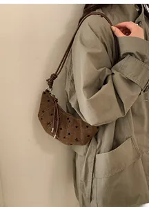 Dettaglio di una borsa a tracolla marrone a pois con ricami floreali su tessuto lana