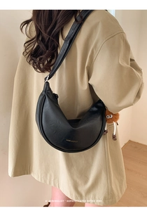 Détail du sac croissant en similicuir noir avec un charmant pendentif monstre en peluche